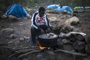  In this Sunday, Nov. 9, 2014 file photo, a Guinean immigrant cooks dinner at a clandestine immigrant camp located at the Mount Gourougou, in the Moroccan province of Nador. Moroccan security forces have arrested hundreds of people in a sweep through a mountainous area where migrants had been living near the Spanish coastal enclave of Melilla, activists said Wednesday, Feb. 11, 2015. The Moroccan Association for Human Rights said that 1,200 migrants had been detained and most bussed to remote parts of the country in the south in an apparent effort to prevent them from trying cross into the Spanish enclave. (AP Photo/Santi Palacios, File) 