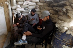 Free Syrian Army fighters use their smartphones behind sandbags in the Al-Maysar neighbourhood of Aleppo May 3, 2014. REUTERS/Jalal Al-Mamo (SYRIA - Tags: CIVIL UNREST MILITARY POLITICS SOCIETY CONFLICT) - RTR3NNM2